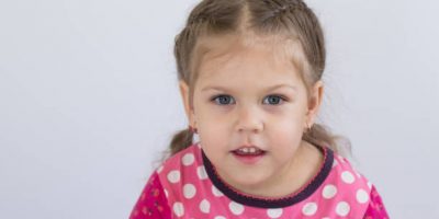 Portrait of caucasian child of three years old looking at camera with shiny eyes on white background